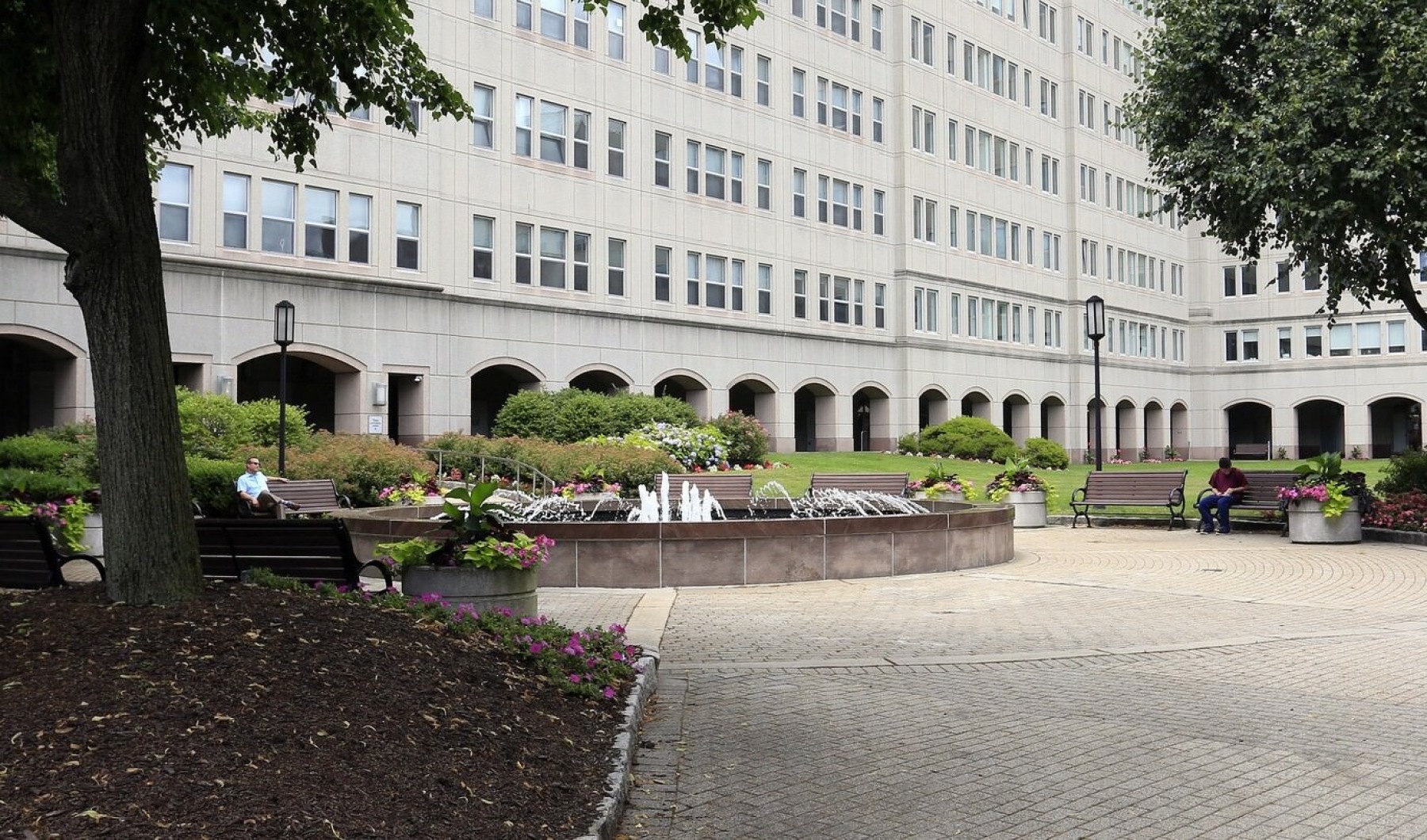 a large building with a fountain and trees